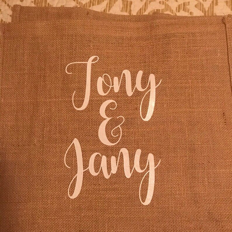 May include: A burlap banner with the text "Tony & Jany" written in white cursive font.