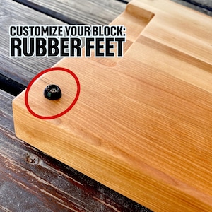 Puede incluir: Primer plano de una tabla de cortar de madera con un pie de goma negro. El texto "CUSTOMIZE YOUR BLOCK: RUBBER FEET" se muestra en negrita, en letras negras sobre el pie de goma. El pie de goma está resaltado con un círculo rojo.