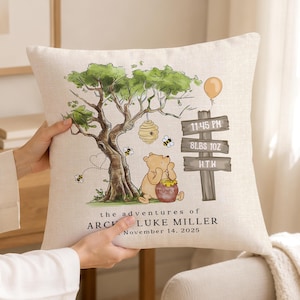 May include: A square throw pillow featuring a printed illustration of a bear holding a honey pot under a tree with a beehive. A wooden signpost displays 11:45 PM, 8LBS 10Z, and H.T.W. Text reads: the adventures of ARCHIE LUKE MILLER November 14, 2025.