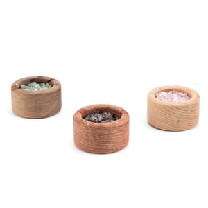 May include: Three small wooden bowls filled with different colored crystals. The bowls are made of light brown wood and have a natural, rustic look.