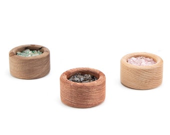 May include: Three small wooden bowls filled with different colored crystals. The bowls are made of light brown wood and have a natural, rustic look.