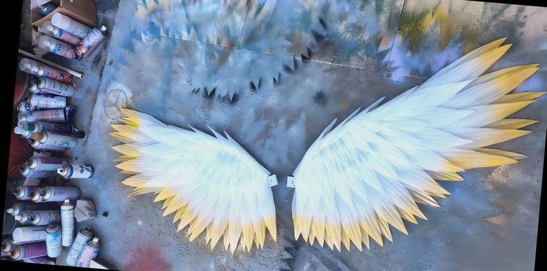 May include: A pair of large, stylized wings featuring layered, pointed feathers that transition from a crisp white at the base to a soft yellow at the tips. The wings are displayed flat, showing a symmetrical arrangement of individual feather segments.