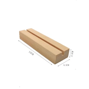Peut inclure: Un pr&eacute;sentoir en bois avec une fente pour tenir des cartes ou des photos. Il mesure 15 cm de long, 4,5 cm de large et 2,5 cm de haut.