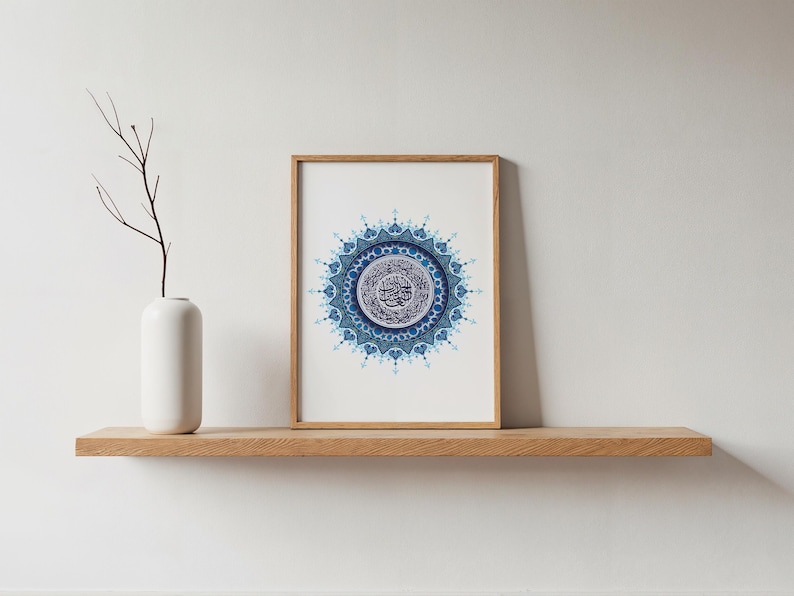 Affiche islamique minimaliste représentant la Sourate Al Fatiha en mandala bleu, encadrée en bois clair et posée sur une étagère moderne. Cette décoration murale coranique s’intègre parfaitement dans un intérieur épuré, scandinave ou contemporain. Elle répond au besoin d’un art islamique discret mais puissant, apportant sérénité et élégance à votre maison. Fichier numérique haute qualité 300 DPI prêt pour impression professionnelle.