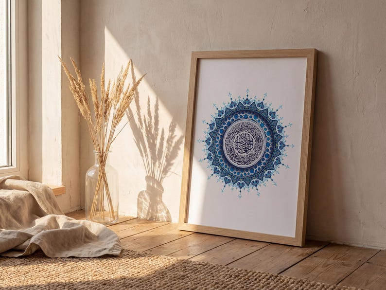 Décoration murale islamique représentant la Sourate Al Fatiha en calligraphie arabe au cœur d’un mandala bleu détaillé. Mise en scène dans un salon lumineux au style naturel et minimaliste, cette affiche coranique crée une ambiance chaleureuse et spirituelle. Parfaite pour un intérieur moderne musulman, elle répond au besoin d’une décoration élégante, apaisante et significative. Téléchargement numérique haute résolution 300 DPI prêt à imprimer.