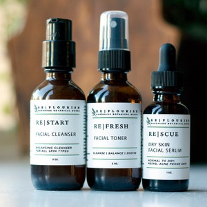 May include: Three amber glass bottles with black pump tops and labels. The bottles are labeled "RE|START Facial Cleanser", "RE|FRESH Facial Toner", and "RE|SCUE Dry Skin Facial Serum".
