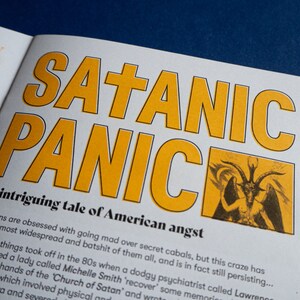 May include: A book cover with the title "SATANIC PANIC" in large yellow letters. The cover features a black and white illustration of a devil with horns and wings. The text below the title reads "An intriguing tale of American angst".