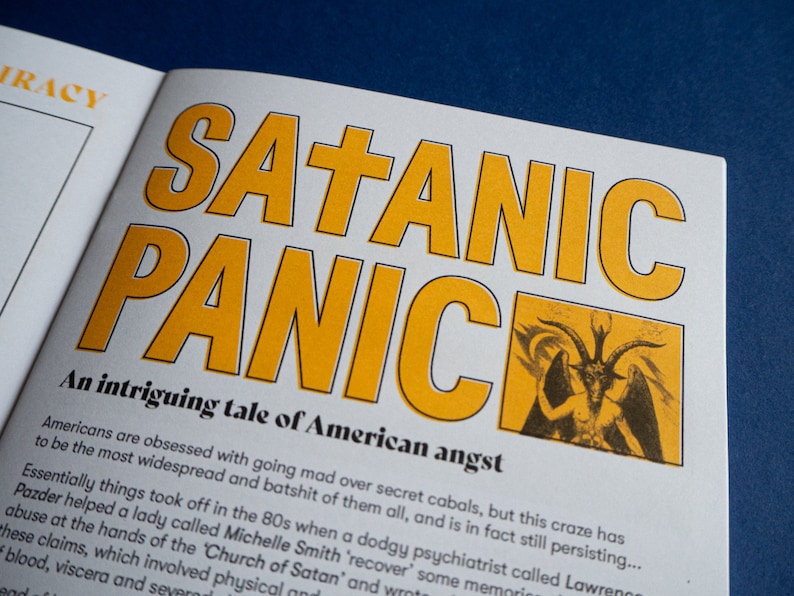 May include: A book cover with the title "SATANIC PANIC" in large yellow letters. The cover features a black and white illustration of a devil with horns and wings. The text below the title reads "An intriguing tale of American angst".
