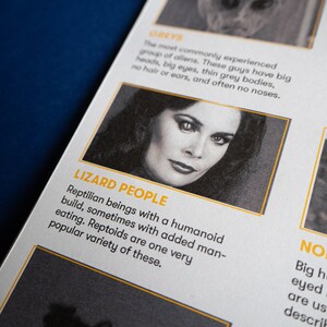 May include: A close-up of a magazine page with a black and white photo of a woman with dark hair and large eyes. The text on the page reads "Lizard People" and describes them as reptilian beings with a humanoid build.
