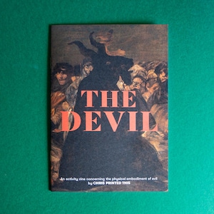 May include: A zine titled "THE DEVIL" with a painting of a group of people on the cover. The text reads "An activity zine concerning the physical embodiment of evil by CHRIS PRINTED THIS."