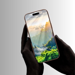 May include: A smartphone with a metallic copper-colored frame displaying a vibrant landscape image of green mountains and a bright sky. The screen features the text "Go confidently in the direction of your DREAMS" in a dark, elegant font.