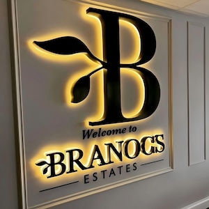 K&ouml;nnte beinhalten: Ein schwarz-wei&szlig;es Schild mit einem stilisierten Buchstaben B und einem Blattdesign. Das Schild lautet "Willkommen bei Branocs Estates".