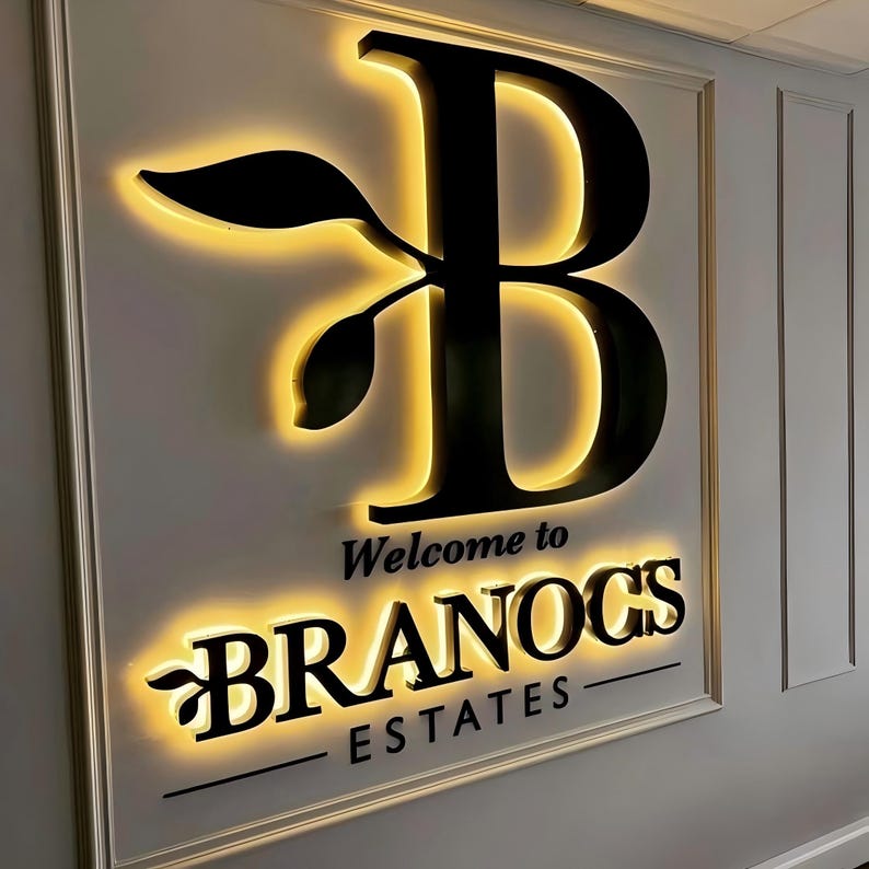 K&ouml;nnte beinhalten: Ein schwarz-wei&szlig;es Schild mit einem stilisierten Buchstaben B und einem Blattdesign. Das Schild lautet "Willkommen bei Branocs Estates".