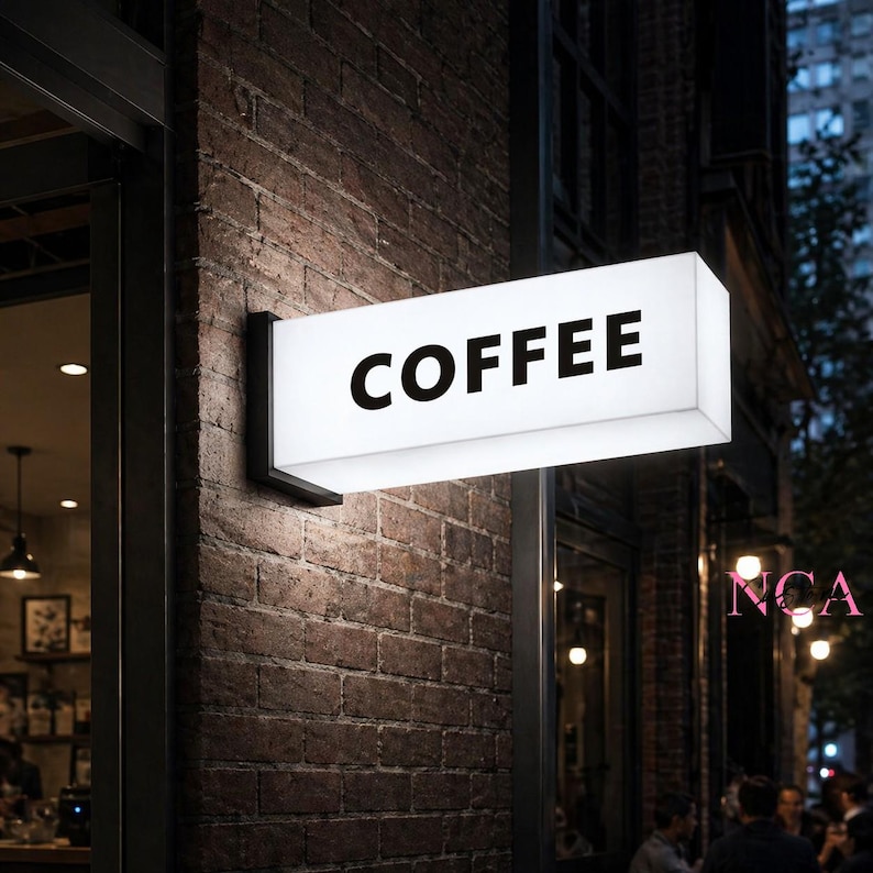 Puede incluir: Un letrero rectangular iluminado con la palabra "COFFEE" en letras negras y en negrita est&aacute; montado en una pared de ladrillo. El letrero es blanco y est&aacute; iluminado desde dentro. El letrero est&aacute; sujeto a la pared con un soporte de metal negro.