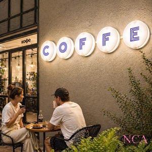 Puede incluir: Escena de un caf&eacute; al aire libre al anochecer. La palabra "COFFE" se muestra en letreros circulares iluminados con letras azules. Una pareja est&aacute; sentada en una mesa peque&ntilde;a, bebiendo bebidas. El caf&eacute; tiene grandes ventanales y un exterior de tonos neutros.
