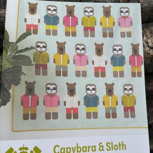 May include: A quilt pattern featuring capybaras and sloths wearing vacation shirts and shorts. The pattern is titled "Capybara & Sloth" and is by Elizabeth Hartman. The text also states that the pattern uses conventional patchwork techniques and does not require templates or paper piecing.