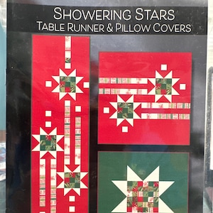 May include: A quilting pattern booklet for a table runner and pillow covers featuring a red and green star design. The title of the pattern is "Showering Stars" and the designer is Robin Pickens.