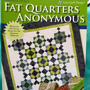 May include: A book titled "Fat Quarters Anonymous" with a green cover and a quilt design on the front. The book title is in white text with a black outline. The subtitle is "Discover the Seven Steps for Fat Quarter Addicts!" and is in a white starburst shape. The quilt design is a patchwork of green, blue, and yellow squares. The book also has a green ribbon with the text "A Seven Step Program" printed on it.