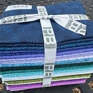 May include: A stack of 14 fabric squares in various shades of blue, purple, green, and white. The fabric is tied together with a white ribbon and a label that reads "P&B Textiles" and "www.pbtex.com".