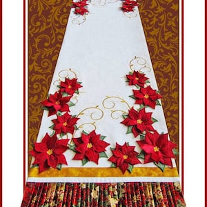 May include: A white table runner with a gold border and red poinsettia embroidery. The runner has a pleated bottom with a red, green, and gold floral pattern. The text "Poinsettia Table Runner" is at the top of the image. The text "A Janine Babich Design" is at the bottom of the image.