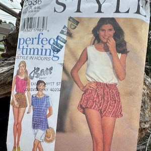 May include: A sewing pattern envelope labeled 2636 Style Perfect Timing. The front displays illustrations of a sleeveless top and shorts, along with a photograph of a person wearing a white sleeveless top and patterned red shorts with a leaf design.