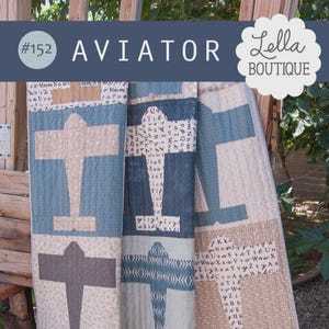 May include: A patchwork quilt with an aviation theme. The quilt features large airplane designs in shades of blue, gray, and cream. The word "AVIATOR" is displayed in large letters at the top, along with the number "#152" and the "Lella Boutique" logo.
