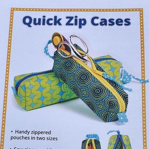 May include: Two zippered fabric pouches with yellow zippers and blue patterned fabric. One pouch is open, holding scissors. The text "Quick Zip Cases" is at the top of the image. The pouches are in two sizes.