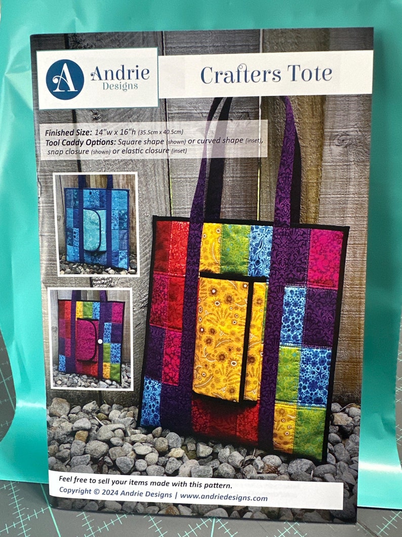 May include: A colorful tote bag with a tool caddy pocket. The tote bag is made of patchwork fabric in shades of red, pink, purple, yellow, green, and blue. The tote bag is 14 inches wide and 16 inches high. The tool caddy pocket is square shaped and has a snap closure. The tote bag is made with a pattern that can be used to create similar bags.