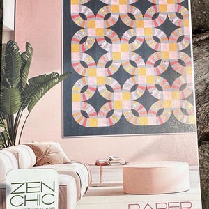 May include: A white ceramic mug with a black handle and the text "But First, Coffee" in a bold, black font. The mug is set against a blurred background, highlighting its clean design.