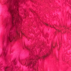 May include: A close-up of a pink fabric with a tie-dye pattern. The fabric has a soft, textured feel and is perfect for crafting projects.