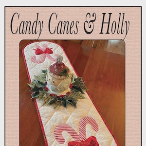May include: A quilted Christmas table runner with candy cane and holly designs. The runner features red and white candy canes, a decorative centerpiece, and the text "Candy Canes & Holly" at the top.