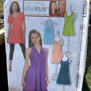 May include: A McCall's M6031 sewing pattern envelope for size E (14-16-18) featuring illustrations of various dress and top styles. The cover displays a coral tunic, a purple halter dress, a light blue halter top, a lime green top, and two dresses.