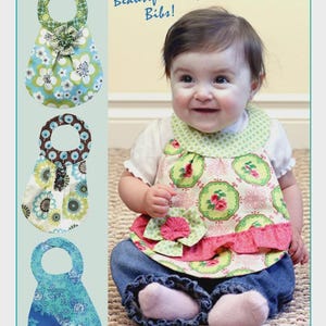 May include: A sewing pattern for baby bibs titled Beautiful Baby Bibs! P181, featuring three distinct bib designs with floral and geometric patterns in shades of green, blue, brown, and pink, along with fabric flower embellishments and ruffles.