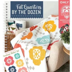 May include: A spiral-bound book titled "Fat Quarters by the Dozen" with a floral quilt and sticker set. The quilt features large yellow, blue, and orange flower designs on a white background. A bonus sticker set is included.