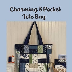 May include: A patchwork tote bag featuring a variety of blue, green, and white floral and geometric fabric patterns. The bag has dark blue straps and the text Charming 8 Pocket Tote Bag is displayed above the bag in dark brown lettering.