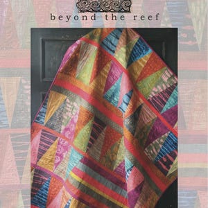 May include: A colorful quilt with a geometric design, featuring triangles in various colors like blue, green, pink, and orange. The quilt has the words "beyond the reef" and "tattoo" in the image.