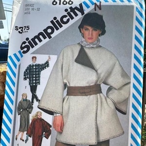 May include: A Simplicity 6166 sewing pattern envelope for a miss size 10-12. The cover features an illustration of a light gray wrap coat with a dark gray interior, wide sleeves, a brown belt, and visible blanket stitching along the edges.
