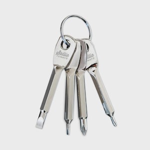 May include: A set of four silver-colored mini screwdrivers attached to a key ring. Each screwdriver has a different tip: flathead, Phillips head, and two other specialized tips. The text "Sallie Tomato" is printed on the head of each screwdriver.