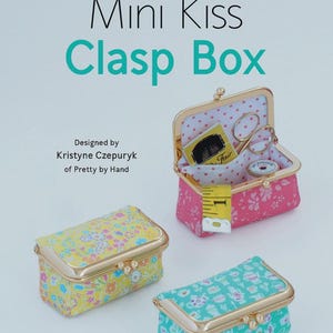 May include: Mini Kiss Clasp Boxes in yellow, pink, and teal floral patterns with gold-colored clasps. One box is open, revealing a tape measure, scissors, and other sewing notions. The text "HARDWARE INCLUDED" and "Mini Kiss Clasp Box" are visible.