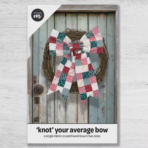 May include: A decorative bow made of fabric with a multi-colored patchwork pattern featuring squares of red, green, white, and grey with various geometric prints. The bow is attached to a circular wreath made of brown twisted twigs and branches.