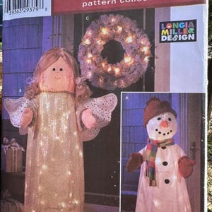 May include: A Simplicity Holiday pattern collection envelope 4335 featuring illustrations of a light-up angel with gold mesh wings, a light-up snowman with a colorful scarf and brown hat, and a circular wreath decorated with small glowing lights.