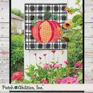 May include: A square wall hanging featuring a black and white buffalo check background with a central orange pumpkin applique. The pumpkin has a green stem and curly vines, with a dotted orange center panel and textured red outer sections.