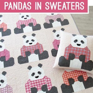 May include: A quilt and pillow featuring panda bears wearing plaid sweaters. The pandas are black, white, and gray, with red and pink plaid sweaters. The text "PANDAS IN SWEATERS" is displayed in a pink banner.