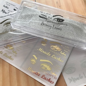 May include: Clear plastic eyelash cases with silver glitter inserts and gold lettering. The cases and stickers read "Miracle Lashes" and "Life is short but your lashes shouldn't be". The image shows multiple cases and stickers.