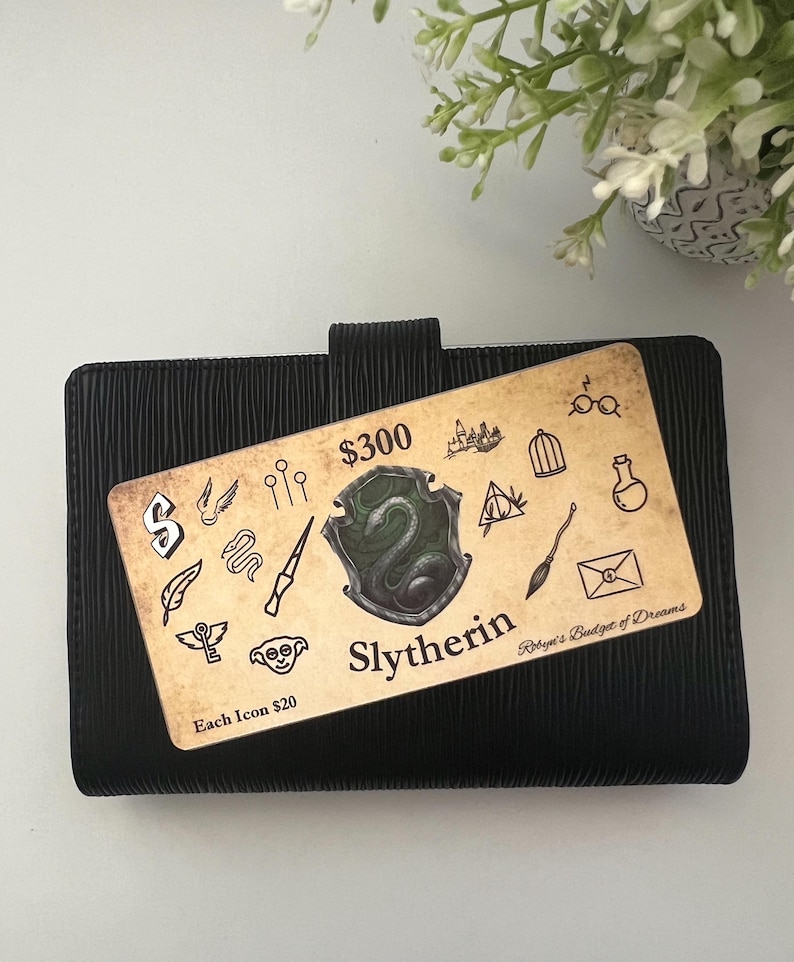 May include: A brown and gold card with a green and silver Slytherin crest and various Harry Potter themed icons. The card reads "$300" and "Each Icon $20". The card also reads "Slytherin" and "Robyn's Budget of Dreams".