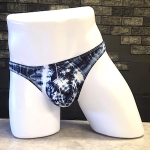 Könnte beinhalten: Ein Thong-Slip im Batik-Look in Blau- und Weißtönen wird auf einer weißen Schaufensterpuppe präsentiert. Die Unterwäsche hat eine niedrige Taille und einen schmalen Bund. Der Stoff hat ein Wirbelmuster.