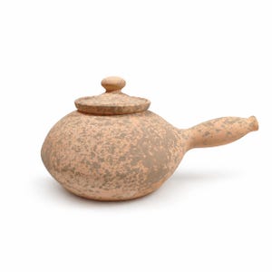 May include: A side-handled teapot with a rounded body and a matching lid, featuring a speckled terracotta and grey finish. The vessel has a wide, low-profile shape with a short, tapered handle extending from the side, crafted from clay.