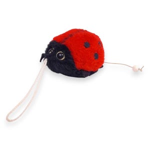 May include: A plush ladybug toy with a red body, black spots, and a black head. The toy has large, round eyes and a white string attached. The ladybug is a classic children's toy.