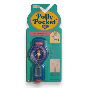 May include: A vintage Polly Pocket "Pixie in Her Pendant" toy, still in its original packaging. The teal and pink packaging features the Polly Pocket logo, a small doll, and a pendant necklace. The pendant contains a miniature doll and accessories.