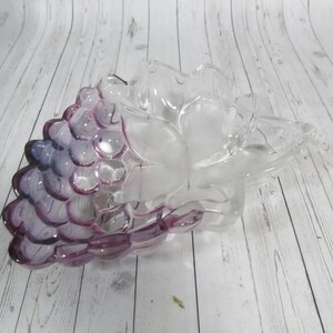 May include: A clear glass grape-shaped bowl with a purple tint. The bowl is designed to look like a bunch of grapes.